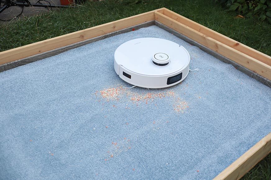 ECOVACS DEEBOT T10 reinigt Haferflocken auf einem Teppich im Saugtest.
